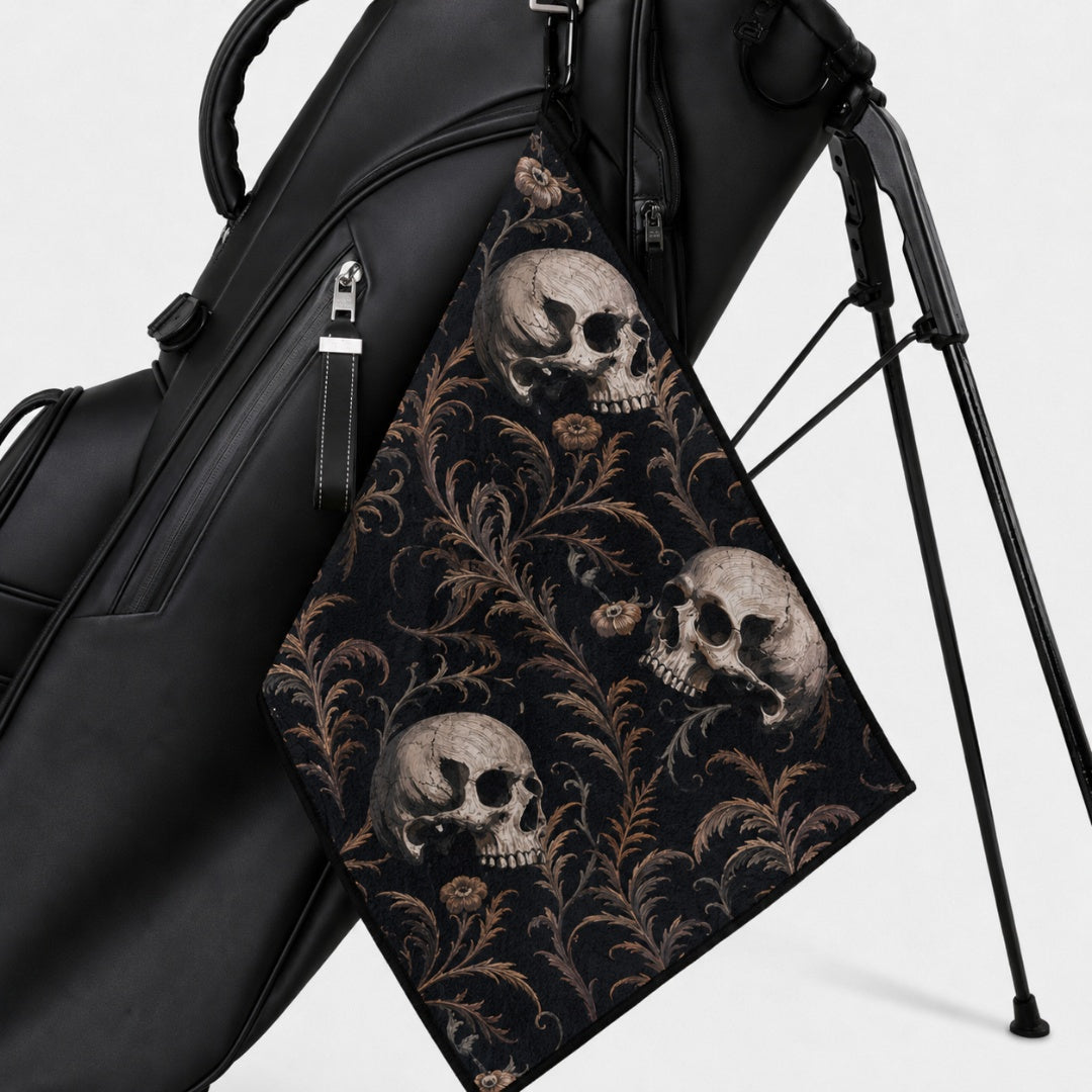 Black golf bag with a skull and floral patterned towel on a white background