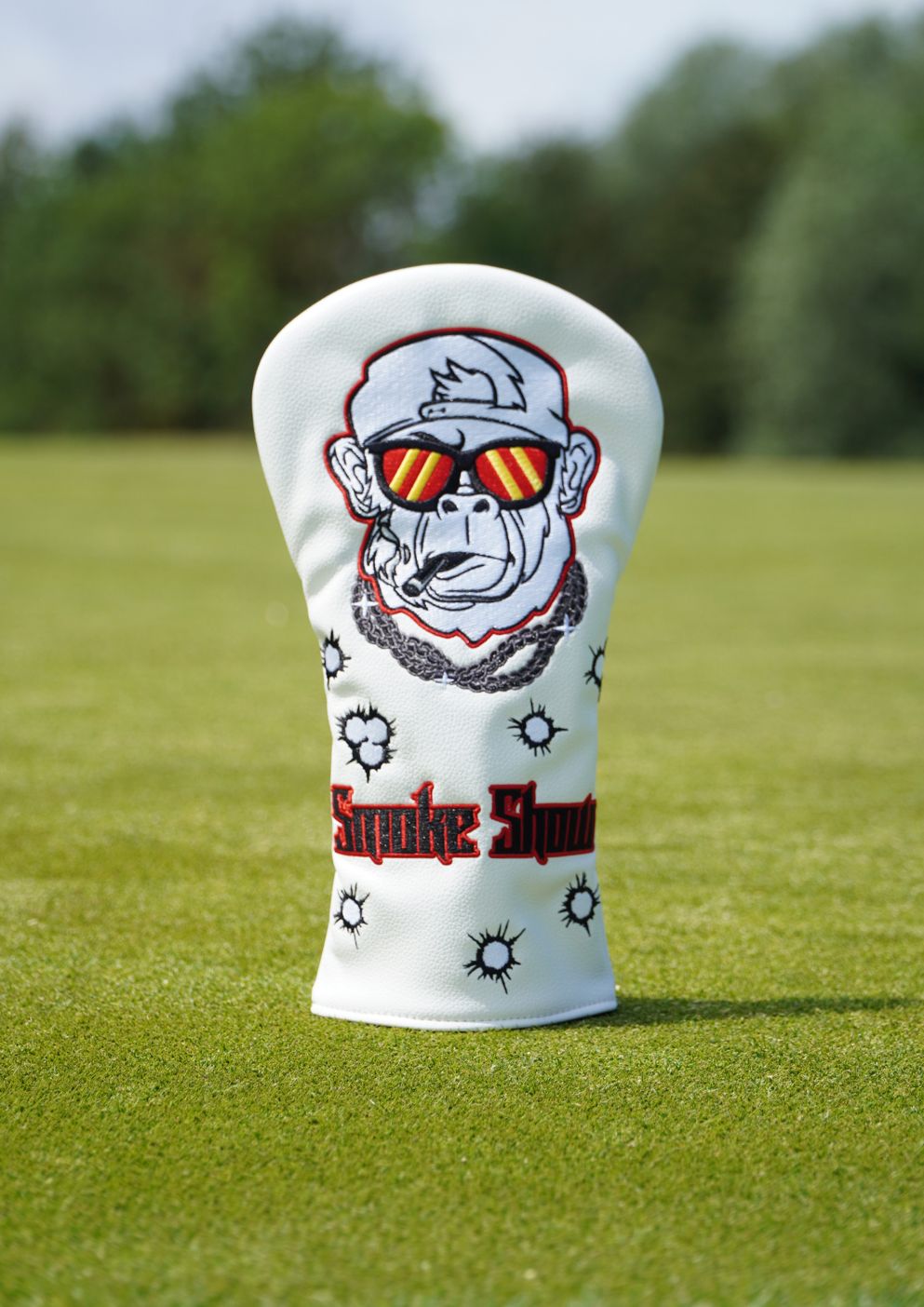 Golf club head cover with monkey design and 'Smoke Show' text on a grassy background