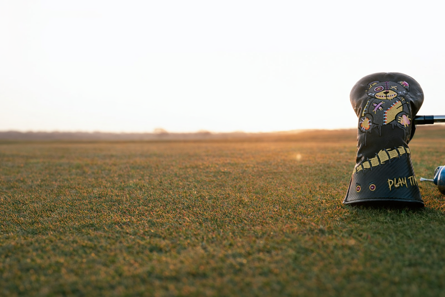 Golf club head cover on a golf course with a blurred background